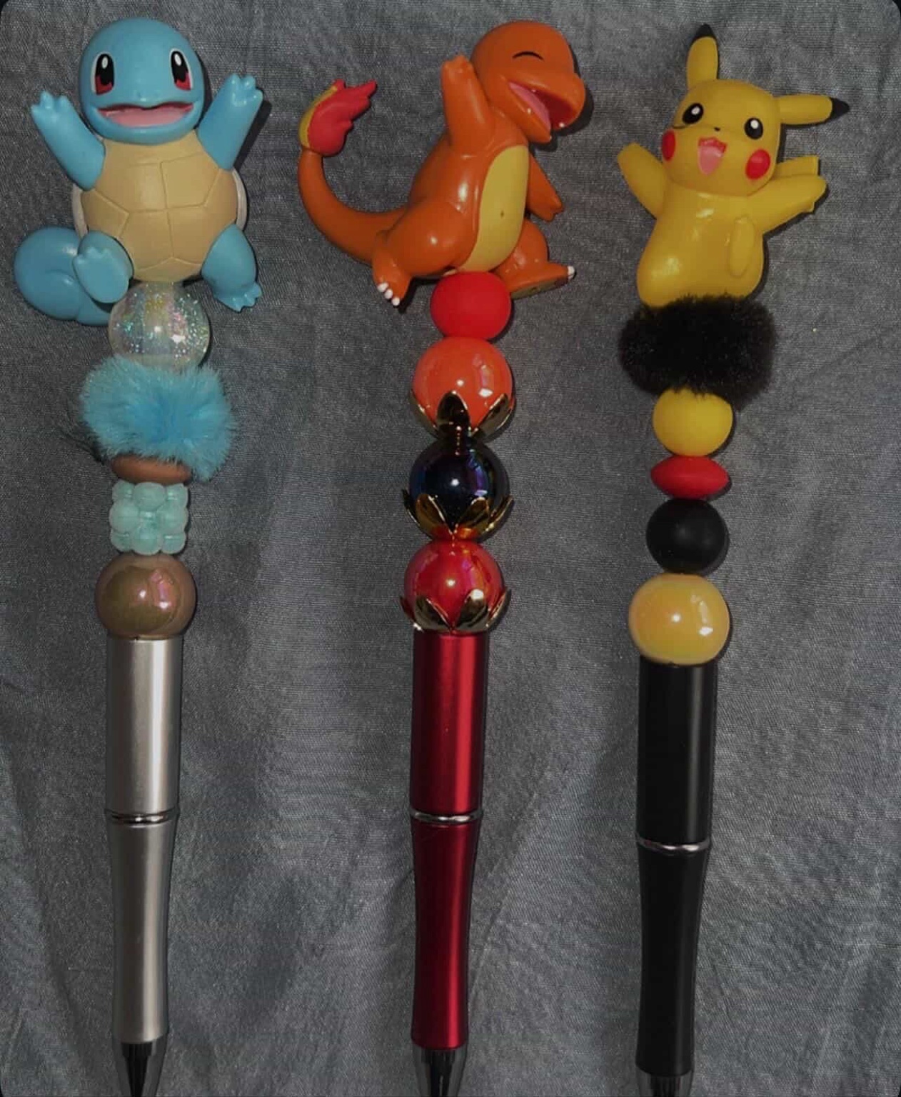 Three creature-inspired pens in blue, red, yellow, and black.
