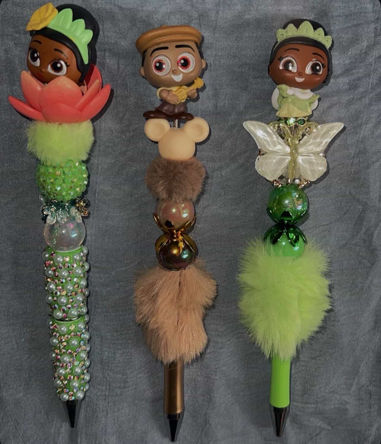 Three green and earth-toned handmade pens with floral and butterfly details.