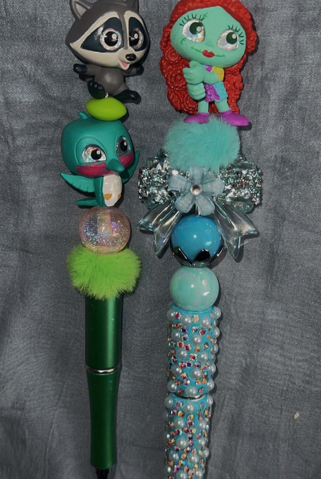 Two playful handmade pens in aqua and green with plush and crystal accents.